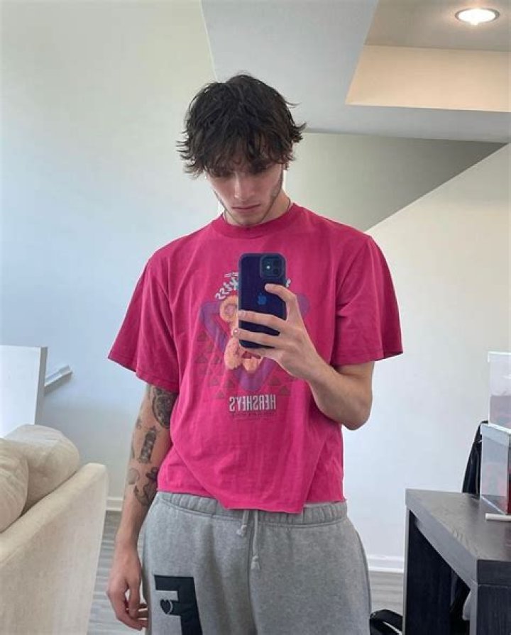 Matthew Sturniolo is wearing a black tee with sleeveless black jacket and posing with his hands crossed.